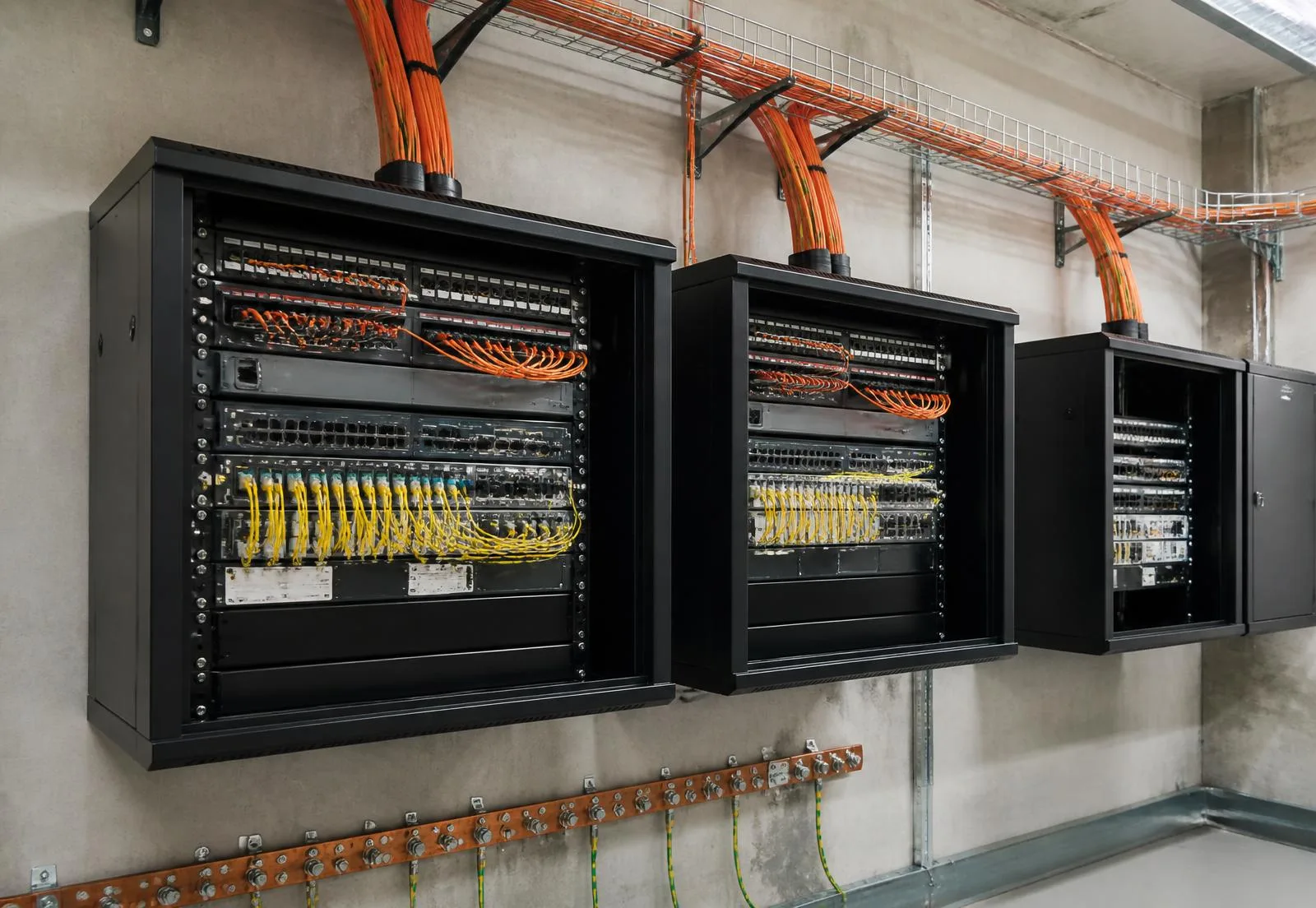 Telecom room with wall-mounted network cabinets, fiber trunks and a grounding busbar
